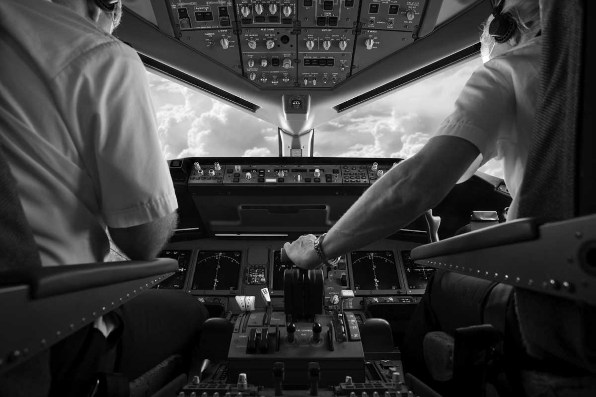 Pilots seated in an aircraft cockpit operating the flight controls