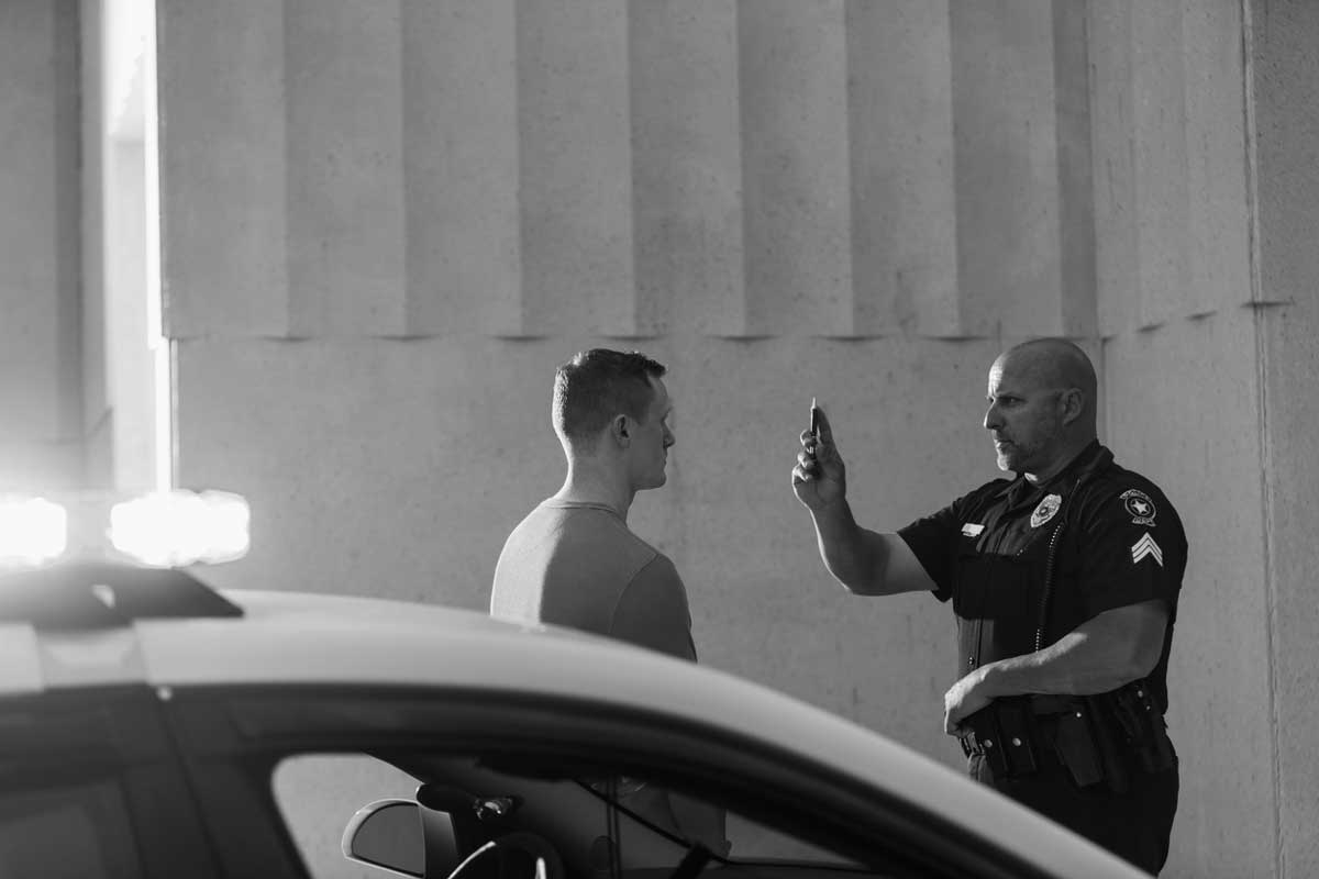 Police officer conducts a roadside sobriety test with a driver beside a patrol car