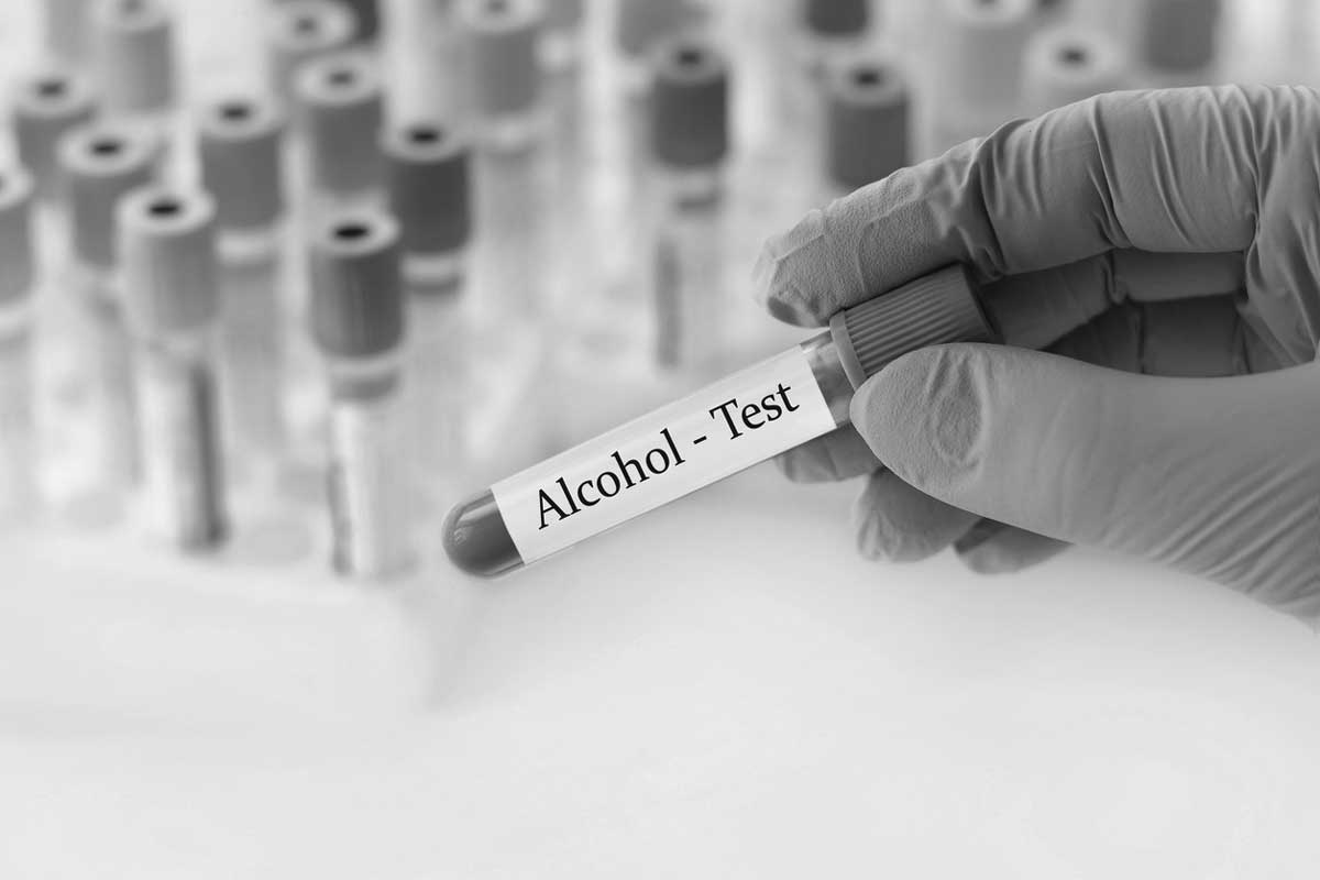 Doctor holding a test blood sample tube with Alcohol test on the background of medical test tubes with analyzes